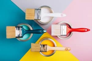 Four open cans of paint with brushes on them on bright